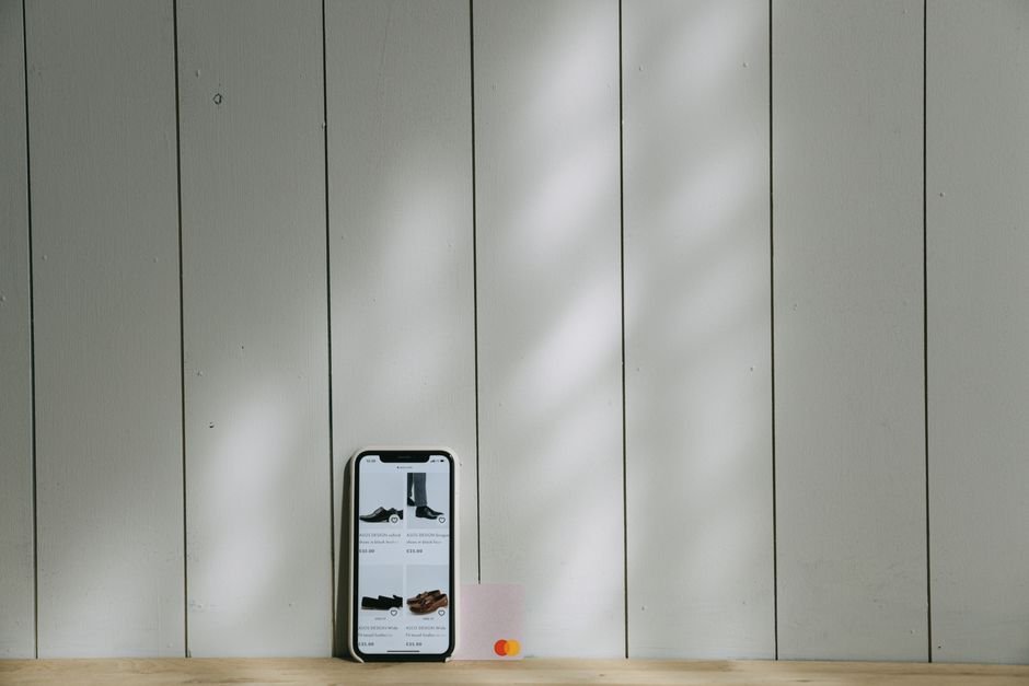 A smartphone and credit card sit on a wooden surface with soft lighting shadows.