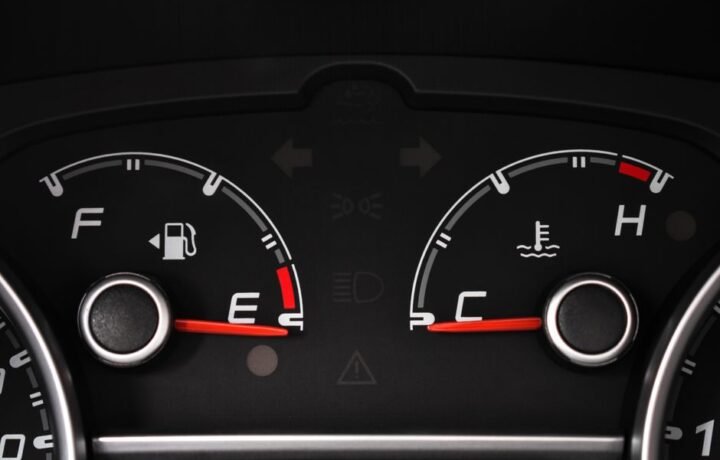 Detailed view of a car's fuel and temperature gauges on dashboard.