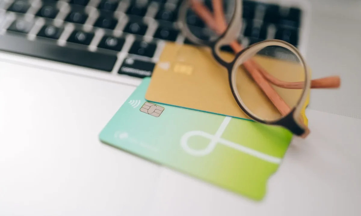 Óculos e cartões de crédito sobre um notebook, reforçando a prevenção fraude pagamento online