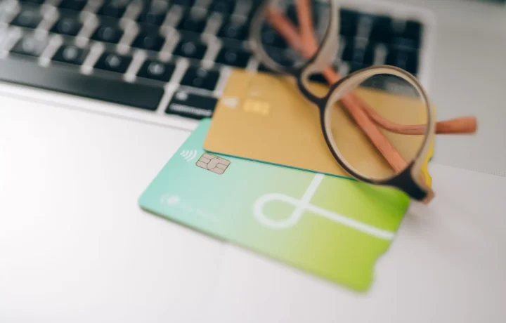 Óculos e cartões de crédito sobre um notebook, reforçando a prevenção fraude pagamento online