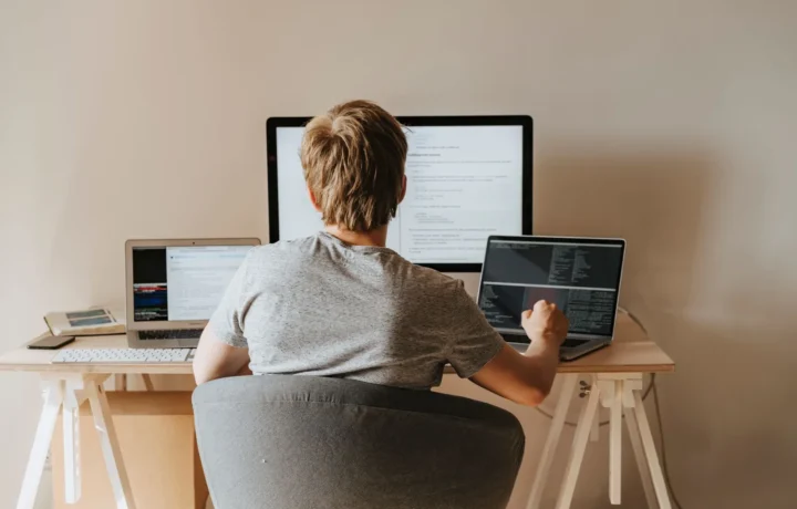 Adolescente programando com vários laptops em espaço de trabalho moderno, representando aprendizado máquina contínuo