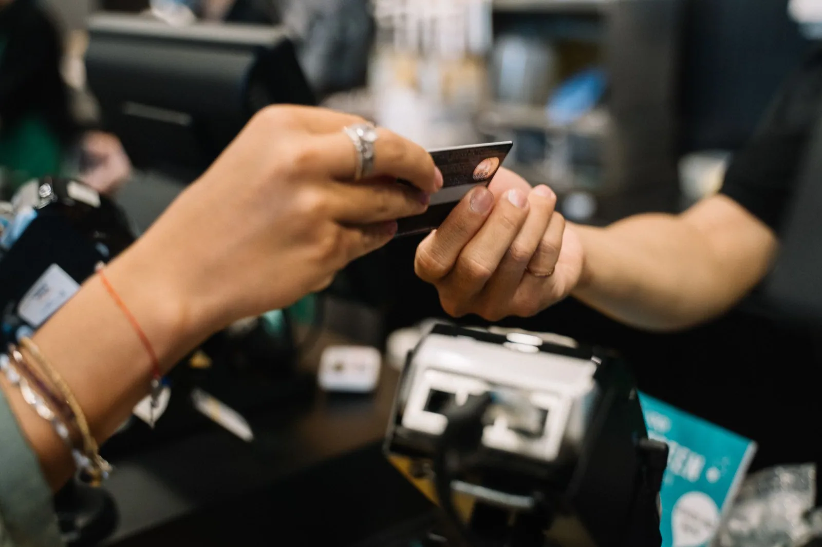 Mãos pagando com cartão de banco no caixa de loja, decisões ao escolher o melhor gateway