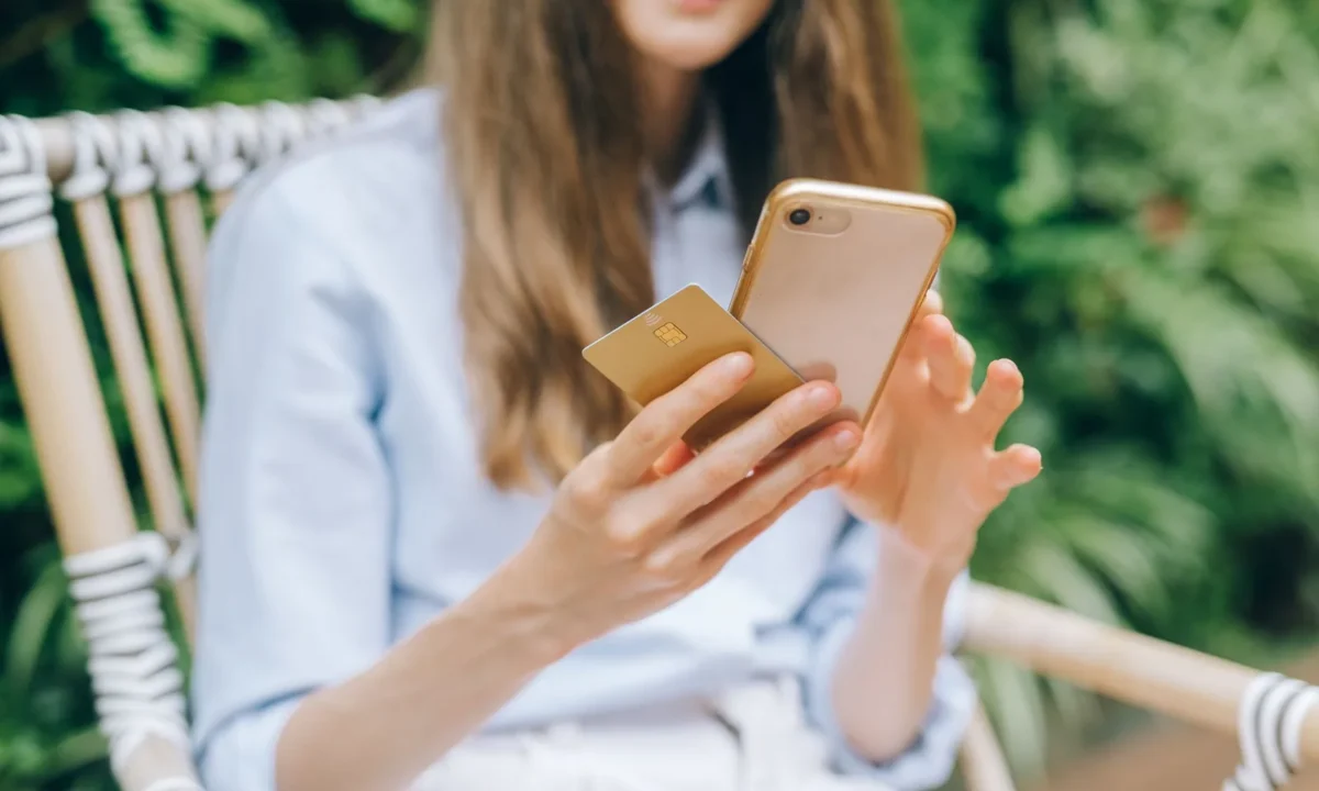 Mulher faz uma compra online com celular e cartão, utilizando pix link de pagamento ao ar livre