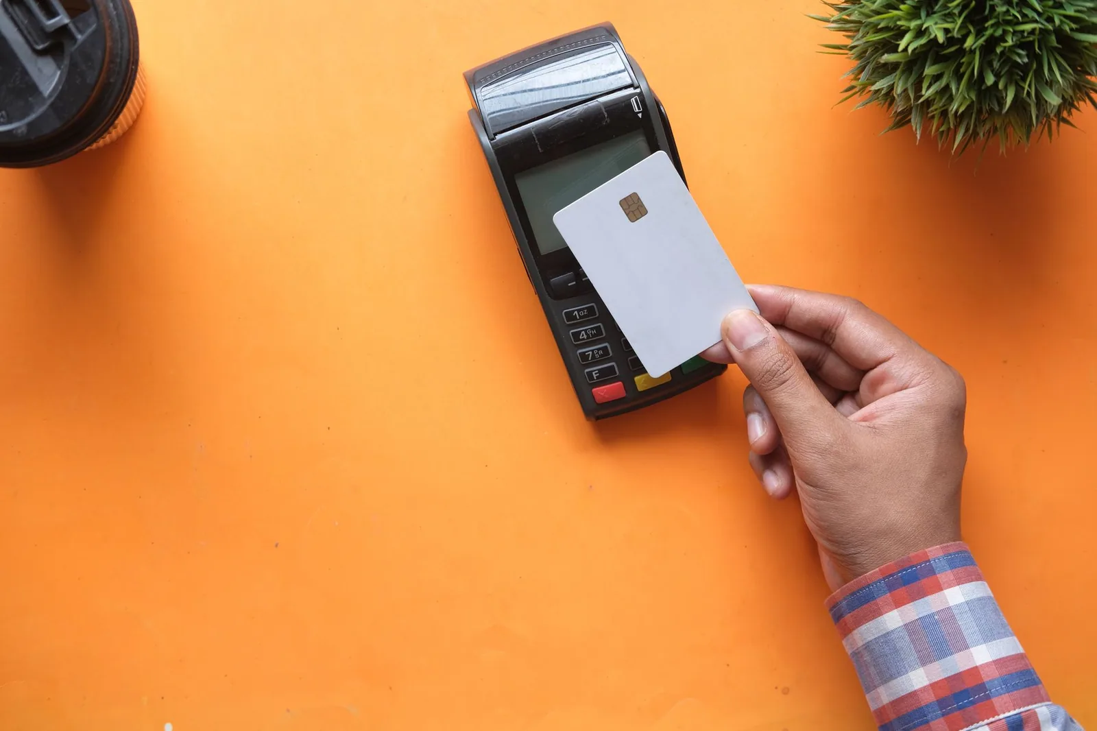 Pagamento por aproximação com cartão de crédito em leitor sobre superfície laranja durante o checkout